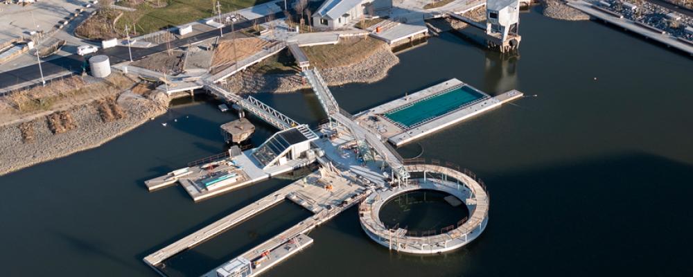 Hamnbadet i Jubileumsparken, Frihamnen 7 i Göteborg. Två naturvattenpooler och en sötvattenpool med naturlig rening, flytande ytan totalt ca 1008 m² och bassängerna sammanlagt ca 580 m². Befintliga pontoner och bassäng har återanvänts. Pontonerna är exceptionellt stora, gjutna och levererade på sänkbar pråm. Speciellt för hamnbadet är också diamantformade pontonen i mitten och den runda pontonen med hopptorn utanpå. Foto: Bluet