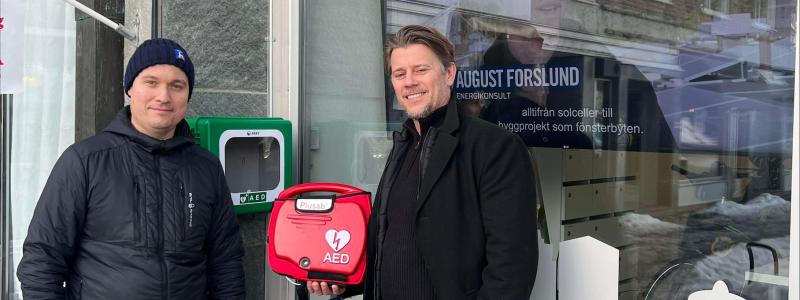 Willy Runnzell, affärsområdeschef på HSB Södra Norrland och Christer Karlsson på Plusab Medical Solution vid hjärtstartaren utanför HSBs kontor i Östersund. Foto: HSB Södra Norrland