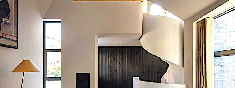 Bild: Interiören präglas av mörk träpanel, natursten och mässingsdetaljer. Ljussättningen är infälld och indirekt. Arkitekterna beskriver detta som en medveten kontrast mot den rationella och återhållsamma estetik som ofta förknippas med små bostäder. Foto: Nick Kane