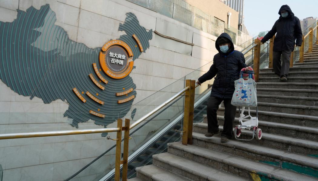 Ng Han Guan/AP/TT: Invånare i Peking går förbi ett delvis nedstängt fastighetskomplex tillhörande Evergrande, som ska likvideras efter ett domstolsbeslut. Arkivbild.