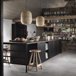 Ett kök att umgås i är svartbetsade Gastro från Ballingslöv. Luckor, lådor och bänkskiva i massiv ek. Den stora köksön rymmer alla kökets funktioner plus smart, luftig matplats. Trivsamt med böcker på väggen och tufft golv i slipad betong. Foto Ballingslöv